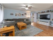 Inviting living room featuring a large sectional sofa, ceiling fan, and wood-look floors at 8401 N 55Th Ave, Glendale, AZ 85302