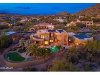 Stunning aerial view of luxury home, pool, putting green and desert landscaping at twilight at 10707 E Cottontail Ln, Scottsdale, AZ 85255