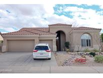 Charming single-story home with a three-car garage, desert landscaping, and a tile roof at 13487 E Gold Dust Ave, Scottsdale, AZ 85259