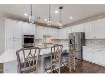 Bright kitchen with white cabinets, stainless steel appliances, quartz countertops, subway tile backsplash, and a kitchen island at 1548 W Windhaven Ave, Gilbert, AZ 85233