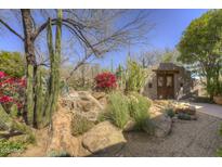 Desert landscape features a waterfall, cactus, and mature trees leading to a wooden gate and hacienda-style home at 3119 Arroyo Hondo --, Carefree, AZ 85377