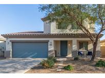 Charming two-story home features a blue door, blue garage door, manicured lawn, and lovely desert landscaping at 42325 W Posada Dr, Maricopa, AZ 85138