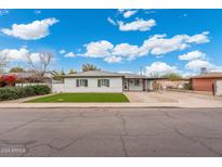 Charming single-story home with manicured front lawn and covered parking under a bright blue, partly cloudy sky at 3021 N Randolph Rd, Phoenix, AZ 85014