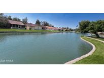 Beautiful waterfront homes line a pond with lush green landscape under a bright blue sky at 416 Leisure World --, Mesa, AZ 85206