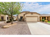 Tan single-story home featuring a two-car garage, desert landscaping, and a mature shade tree at 535 E Yellow Wood Ave, San Tan Valley, AZ 85140