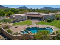 Expansive backyard featuring a sparkling pool, spa, fire pit, lush lawn, and covered patio with desert mountain views at 24688 N 87Th St, Scottsdale, AZ 85255