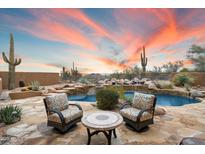 Inviting backyard pool area with comfortable seating and desert landscaping under a vibrant sunset sky at 30600 N Pima Rd # 93, Scottsdale, AZ 85266