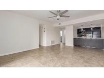 Bright living room with ceiling fan and adjacent kitchen featuring dark cabinetry and tile flooring at 3314 N 68Th St # 247, Scottsdale, AZ 85251