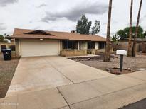 Traditional single-story home with a driveway leading to the two-car garage and front yard landscaping at 5220 E Winchcomb Dr, Scottsdale, AZ 85254