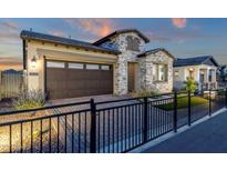 Charming single-Gathering home featuring stone accents, a dark brown garage, and brick paved driveway at 5748 E Sierra Morena St, Mesa, AZ 85215