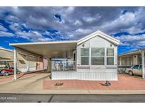 Well-maintained mobile home featuring a covered porch, carport, and low-maintenance landscaping at 7750 E Broadway Rd # 294, Mesa, AZ 85208