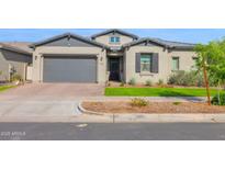 Charming single-story home with gray stucco, complemented by a well-manicured lawn, and a two car garage at 9734 E Spiral Ave, Mesa, AZ 85212