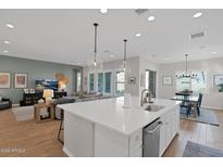 Bright, open kitchen with island seating, white cabinets, and an adjoining living space at 9734 E Spiral Ave, Mesa, AZ 85212