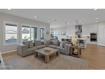 Open-concept living area with large windows, featuring a modern gray sofa and a kitchen island at 9734 E Spiral Ave, Mesa, AZ 85212