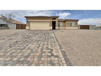 Inviting single-story home featuring a charming facade, paver driveway, gravel landscaping, and an attached two-car garage at 15422 S Sequoia Cir, Arizona City, AZ 85123