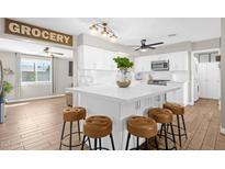 Bright kitchen featuring white cabinets, center island with seating, and modern appliances, complemented by wood-look flooring at 1715 W Carol Ave, Mesa, AZ 85202