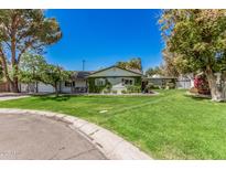 Charming single-story home with lush lawn and vine-covered facade, set under a bright blue sky at 1829 E Orange Dr, Phoenix, AZ 85016