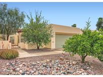 Southwestern-style home with neutral stucco and a two-car garage, with a unique rock garden landscape at 2167 E Aspen Dr, Tempe, AZ 85282