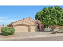 Charming home with a well-maintained lawn and a large three-car garage and beautiful mature landscaping at 7908 W Harmony Ln, Peoria, AZ 85382