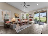 Comfortable living room featuring a sectional sofa, recliner, ceiling fan, and sliding door access to the backyard at 24511 S Golfview Dr, Sun Lakes, AZ 85248