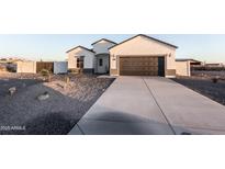 Inviting single-Gathering home featuring a xeriscaped yard and a long concrete driveway leading to the attached garage at 8315 W Concordia Dr, Arizona City, AZ 85123
