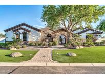 Charming single-story home featuring a stone gatehouse and manicured landscaping at 10059 W Villa Lindo Dr, Peoria, AZ 85383