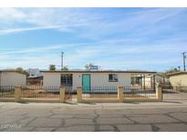 Charming single-story home featuring a fenced yard, desert landscaping, and a vibrant turquoise front door at 1851 E Pleasant Ln, Phoenix, AZ 85042