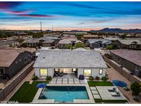 Aerial view of a backyard pool with lounge chairs, turf, and desert landscaping under a vibrant sunset sky at 22372 E Duncan St, Queen Creek, AZ 85142