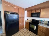 Well-lit kitchen featuring wooden cabinets, black appliances, and tile flooring at 5407 E Hermosa Vista Dr, Mesa, AZ 85215