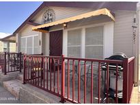 Inviting front porch with a red metal railing, a neutral tan exterior, and awning over the front door at 650 N Hawes Rd # 4609, Mesa, AZ 85207