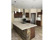Modern kitchen features dark cabinets, stainless steel appliances, stone accents, and a large island at 7163 W Lamar Rd, Glendale, AZ 85303