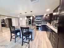 Contemporary kitchen boasts wooden floors, dark cabinets, island with pendant lighting and stainless steel appliances at 7920 E Camelback Rd # 203, Scottsdale, AZ 85251