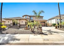 Beautiful two-story home featuring a well-manicured yard with mature palm trees and a circular driveway at 3925 E Vallejo Dr, Gilbert, AZ 85298