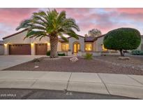 Inviting single-story home with well-maintained landscaping, desert accents, and a charming entryway with a beautiful palm tree at 16927 W Desert Blossom Way, Surprise, AZ 85387