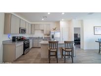 Modern kitchen with gray cabinets, stainless steel appliances, and an island with seating at 2583 N Kenna Pl, Casa Grande, AZ 85122