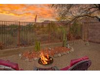 Inviting backyard with fire pit, seating area, desert landscaping, and mountain views at sunset at 10356 E Meandering Trail Ln, Gold Canyon, AZ 85118