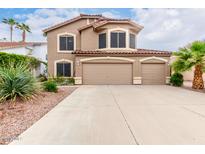 Inviting two-story home features a three-car garage, desert landscaping and a classic stucco facade at 1567 S Western Skies Dr, Gilbert, AZ 85296