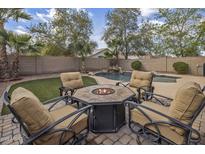 Inviting backyard featuring a pool with a waterfall and fire pit seating area, perfect for entertaining at 45583 W Sheridan W Rd, Maricopa, AZ 85139