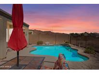 Relaxing pool area with lounge chairs, a red umbrella, and desert views in the backyard at 8377 S Mountain Air Ln, Gold Canyon, AZ 85118