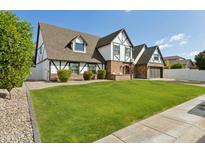 Charming Tudor-style home featuring a well-manicured lawn, brick accents, and a two-car garage at 902 W Claremont St, Phoenix, AZ 85013