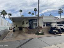 Charming mobile home featuring a covered carport, palm trees, and a well-maintained exterior at 1147 S Sioux Dr, Apache Junction, AZ 85119