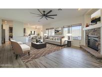 Open-concept living space with fireplace, hardwood flooring, and large windows offering natural light at 16462 W Rowel Rd, Surprise, AZ 85387