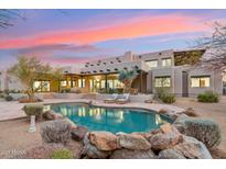 Inviting pool area with rock features and comfortable lounge seating at this luxury property at sunset at 30600 N Pima Rd # 76, Scottsdale, AZ 85266