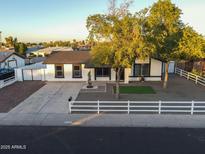 Charming single-story home with well-manicured landscaping, mature trees, and a white picket fence at 7316 W Carol Ave, Peoria, AZ 85345
