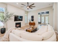 Bright living room featuring a fireplace, modern ceiling fan, and access to the backyard at 9270 E Thompson Peak Pkwy # 381, Scottsdale, AZ 85255