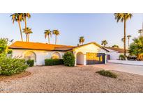 Charming single-story home featuring a desert landscape, palm trees, and a two-car garage at 10640 E Mercer Ln, Scottsdale, AZ 85259