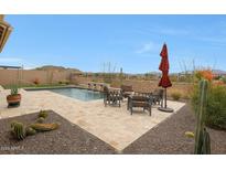 View of pool area featuring a dining set with red umbrella, desert landscaping, and mountain views at 14939 S 185Th Ave, Goodyear, AZ 85338
