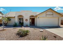 Charming single-story home with arched entryway, low maintenance desert landscaping, and attached two car garage at 4903 E Halifax St, Mesa, AZ 85205