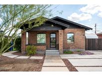 Charming brick home featuring a cozy front porch and beautifully landscaped walkway to the main entrance at 1009 E Garfield St, Phoenix, AZ 85006