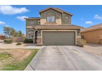 Two-story home with a two-car garage, stone accents, and a well-maintained front yard under a sunny sky at 6409 S 49Th Dr, Laveen, AZ 85339